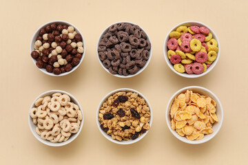 Bowls with different tasty cereals on beige background