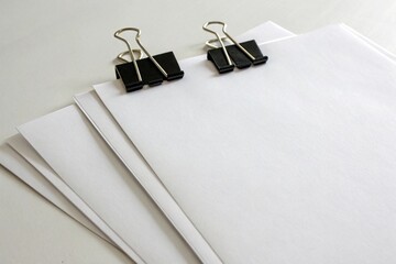 Two white paper sheets with metal paperclip on clean background. Blank notepaper for office, business, education, reminder, messaging, and stationary mockup or design use.