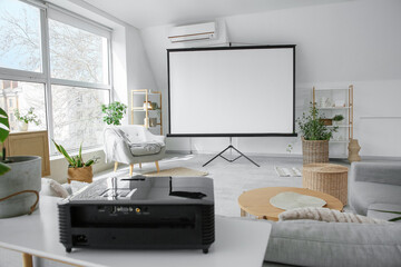 Interior of light room with blank projector screen, armchair and plants