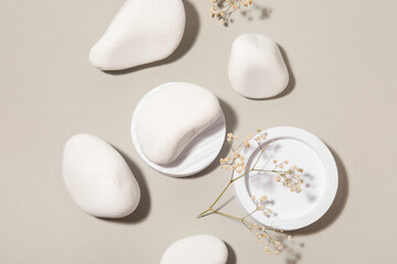Decorative podiums with white pebbles and gypsophila flowers on grey background