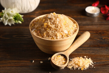 Bowl and spoon with sea salt on brown wooden background, closeup