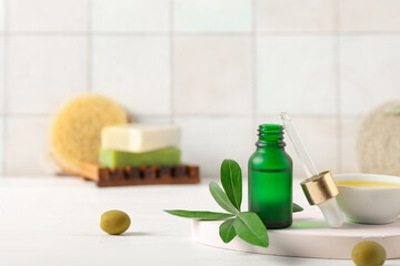 Plaster stand with bottle and bowl of essential olive oil on white grunge background, closeup