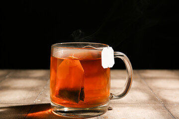 Cup of hot tea on grey tile table against dark wall
