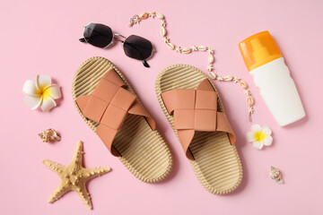 Stylish flip flops with sunglasses, starfish, sea shells, necklace and bottle of sunscreen on pink...