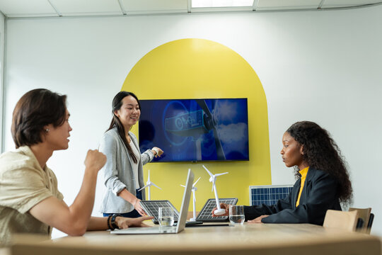 Diverse coworkers pointing at turbine graphics on screen and discussing models in meeting room