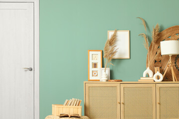 Vases with pampas grass, lamp and photo frames on chest of drawers in living room, closeup