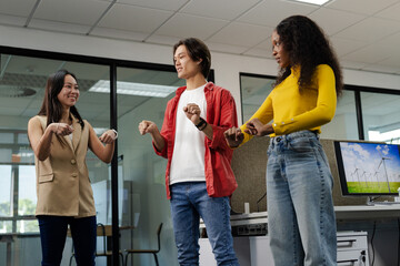 Diverse coworkers copying steering moves at office desk with wind turbine display and smartwatches