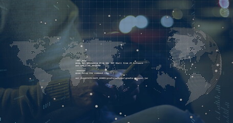 Typing male in striped sweater in low-lit workspace, with smartphone and world map code snippets