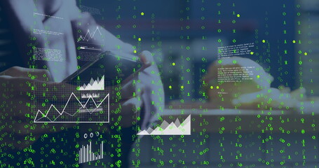 Interacting professional tapping smartphone at office desk with keyboard, charts and binary code