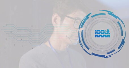 Pointing Korean speaker wearing glasses, lanyard toward firewall icon at tech event, copy space