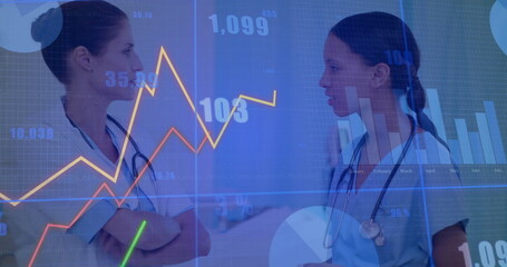 Clinicians wearing scrubs and stethoscopes reviewing patient stats in hallway, with digital charts