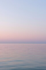 Obraz premium Calm pastel pink and blue horizon over a smooth sea during sunset, creating a serene and minimalistic atmosphere perfect for backgrounds, wellness, relaxation, and nature-themed designs