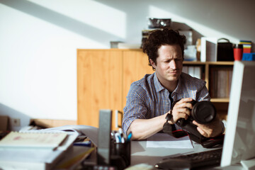 Male photographer reviewing camera in creative office workspace