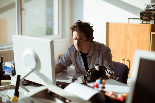 Male photographer reviewing camera in creative office workspace