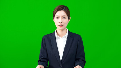 Female announcer reading the news in front of green background.