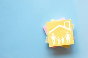 Family life and home insurance concept. House and family icon on a sticky note for planning a...