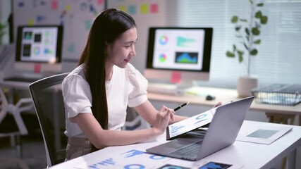 Asian businesswoman analyzing charts on laptop and digital tablet - Powered by Adobe