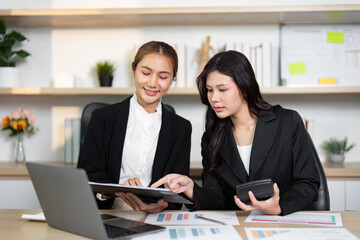Business Collaboration. Two women analyzing financial reports together in a modern office.