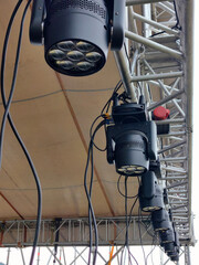 series modern stage lights hang from rigging above performance area, ready to illuminate an outdoor...