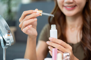 Skin Care Routine. Woman using dropper to apply serum from a bottle.