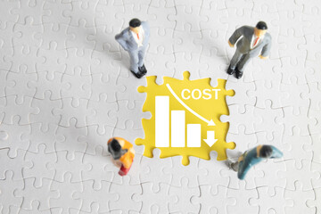 Miniature businessmen standing around a jigsaw puzzle piece with a declining graph and the word...