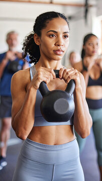Persona joven con cabello rizado levantando kettlebell en posici&oacute;n de fuerza, fondo neutro, postura firme, energ&iacute;a concentrada y expresi&oacute;n determinada durante entrenamiento funcional