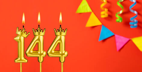 Number 144 birthday candle on an orange background with pennants