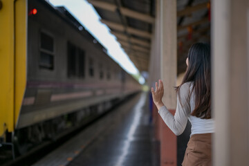 A woman stands on the platform of a train station