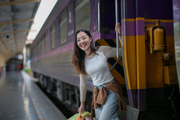 A woman is standing on a train platform with a green bag