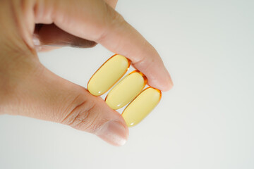 Male hand holding Oil filled capsules, softgel of food supplements, fish oil, omega 3, vitamin E