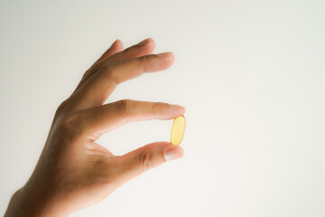 Male hand holding Fish oil capsules with omega 3, omega 9, vitamin D, vitamin E, Cod liver oil