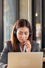 Vertical Women helpdesk CSR call center use headphones talk to customer. Asian woman operator...
