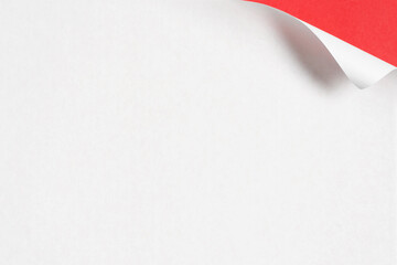Minimalist image of a white paper with its top corner curled to reveal a bright red back. Perfect...
