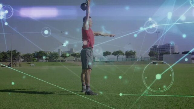 Trainer driving heels and swinging kettlebell from low squat on grass field for strength training