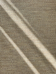 Light patterns on woven fabric showcase intricate texture and design in natural daylight