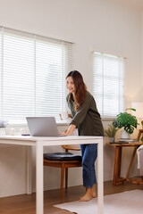 Asian Female office worker or businesswoman standing and honding cup of coffee leaning over a...