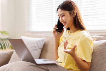 Joyful happy young Caucasian asian woman resting on sofa in apartment call on mobile phone internet...