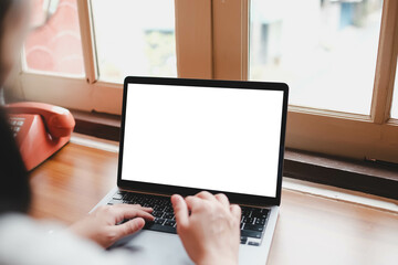 A person typing on a laptop with a blank white screen in a home office with a vintage telephone, blending modern technology and retro style.