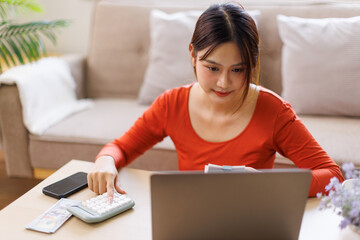 Young asian woman holding pen with bills working for calculate business data, taxes, bills payment,...