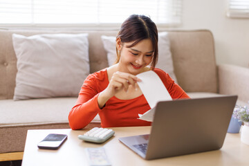 Young asian woman holding pen with bills working for calculate business data, taxes, bills payment,...