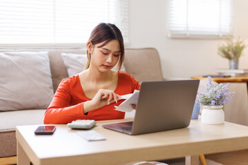 Young asian woman holding pen with bills working for calculate business data, taxes, bills payment,...