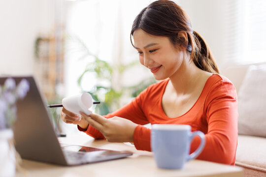 Happy asian woman manage household budget calculate expenses expenditures on machine. Smiling young biracial female pay bills taxes online on computer. Finances concept.
