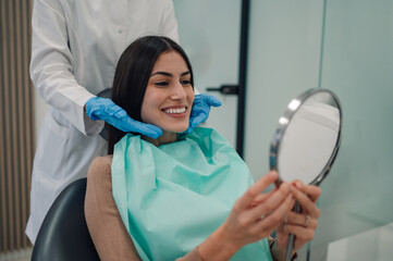 Woman smiling while looking at mirror at dentist office