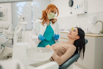 Dentist wearing surgical mask holding dental tools talking to patient