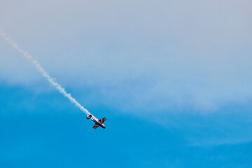 Aerobatic Airplane Performing Smoke Maneuver in Blue Sky