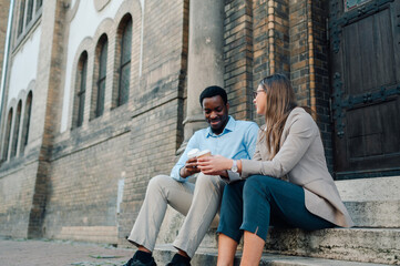 Business colleagues enjoying coffee break on building steps