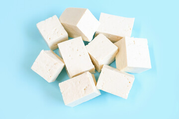 Sliced tofu cubes on blue background close-up top view.
