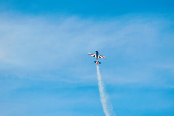 Aerobatic Airplane Performing Smoke Maneuver in Blue Sky