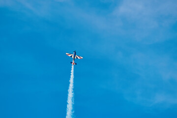 Aerobatic Airplane Performing Smoke Maneuver in Blue Sky