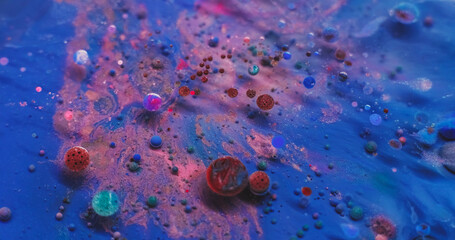 Shiny particles. Paint water. Defocused red pink blue colorful shimmer oil round liquid floating on...